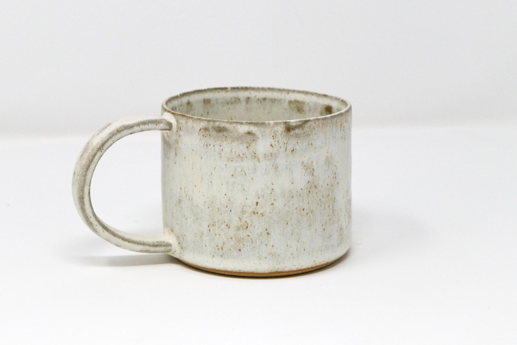 A wide shot of a handmade white speckled mug.