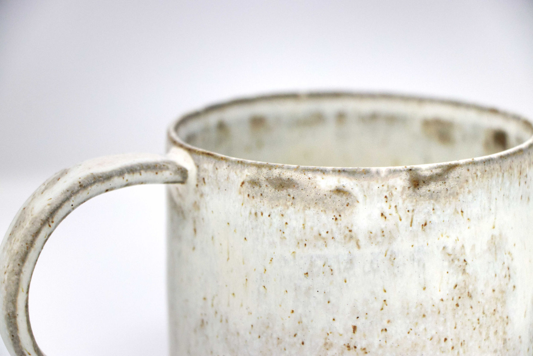 A close-up shot of a handmade white speckled mug, demonstrating the speckle pattern.